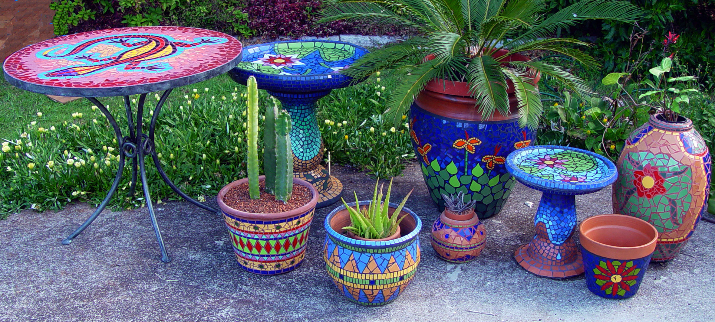 collection of bright, colourful mosaic pots, birdbaths and mosaic table