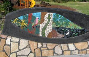 Mosaic landscape scene with carpet snake, galah, pelican and wattle flowers