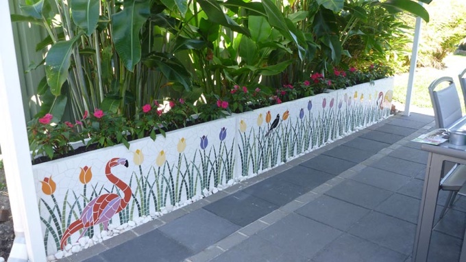 Flamingoes and colourful tulips theme on a white mosaic background on planters