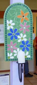 many coloured fflowers mosaic candleholder with a green background