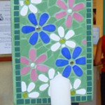 many coloured fflowers mosaic candleholder with a green background